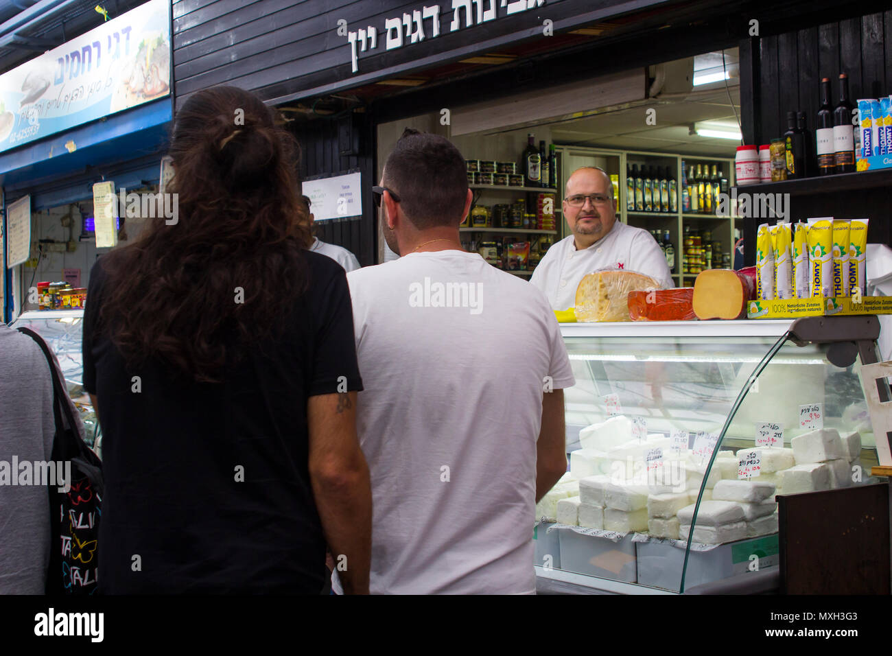 9 de mayo de 2018 un propietario local en sus locales con una selección de quesos de cabra en exhibición en la muy transitada calle mercado de Mahane Yehuda en Jerusalén Foto de stock