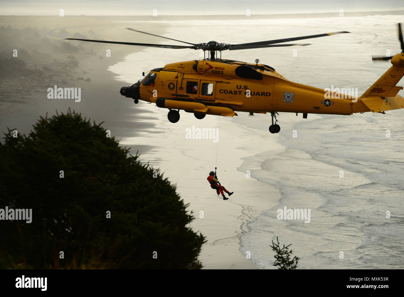 Un técnico de supervivencia de aviación es bajado a un acantilado por un helicóptero MH-60 Jayhawk durante el acantilado capacitaciones rescate cerca de la cabeza del Norte Luz en Ilwaco, Washington, 10 de noviembre, 2016. La capacitación fue parte de la semana de la Escuela de rescate Helicóptero de avanzada. La Guardia Costera de EE.UU. Foto por Petty Officer 1st Class Levi Leer. Foto de stock