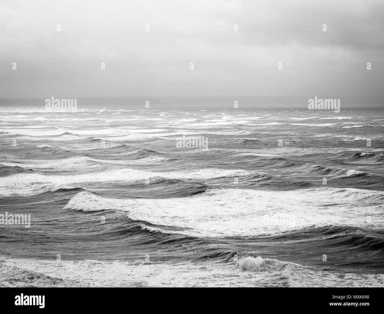 Surf tormentosa oleada, Blanco y negro, Playa Saunton, Devon, Inglaterra Foto de stock
