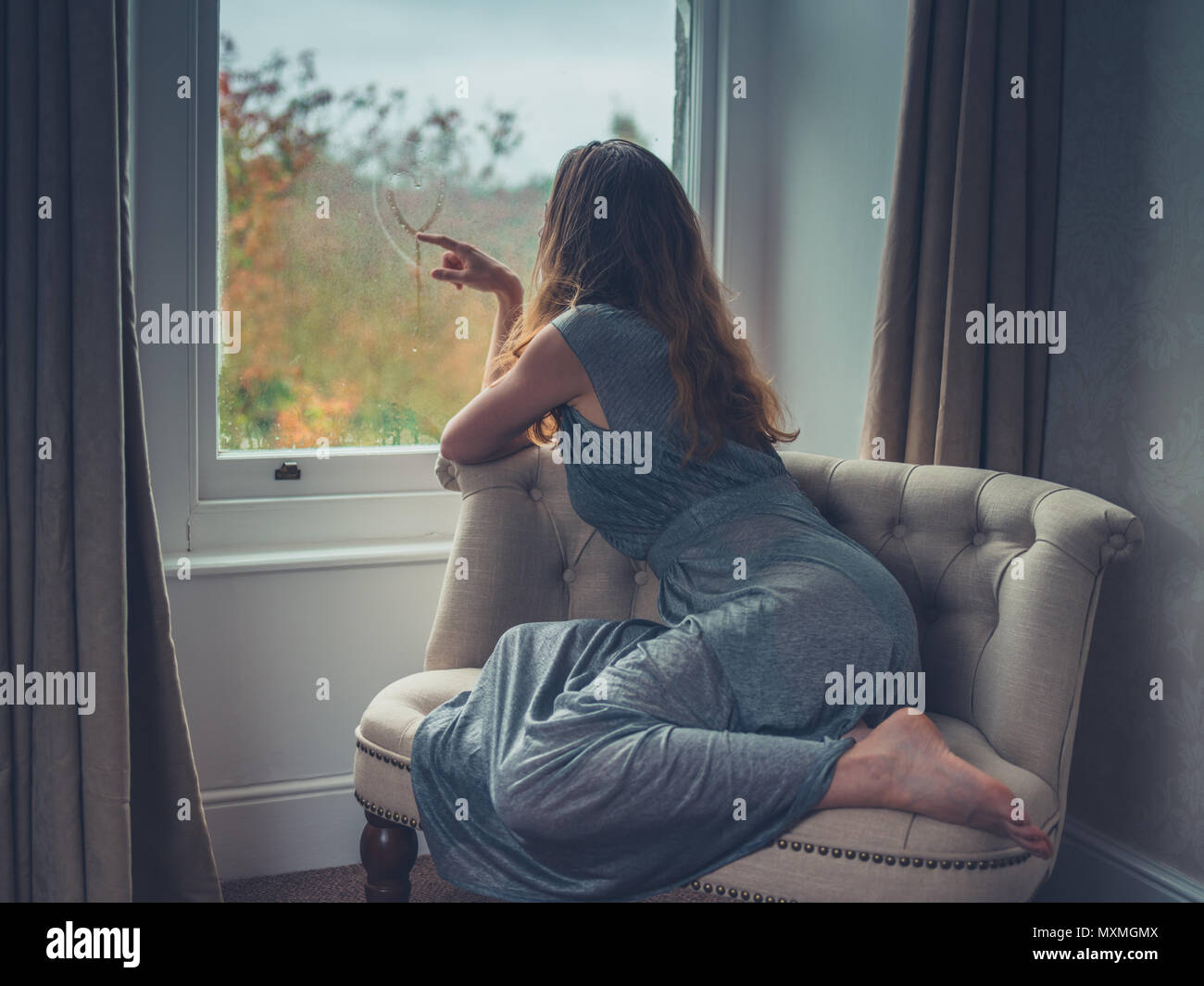 Una joven mujer vistiendo un elegante vestido soñar despierto por la ventana de stock - Alamy
