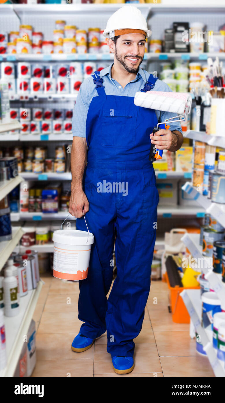Laughing obrero en un mono azul con pintura y pinceles en manos en la  tienda Fotografía de stock - Alamy