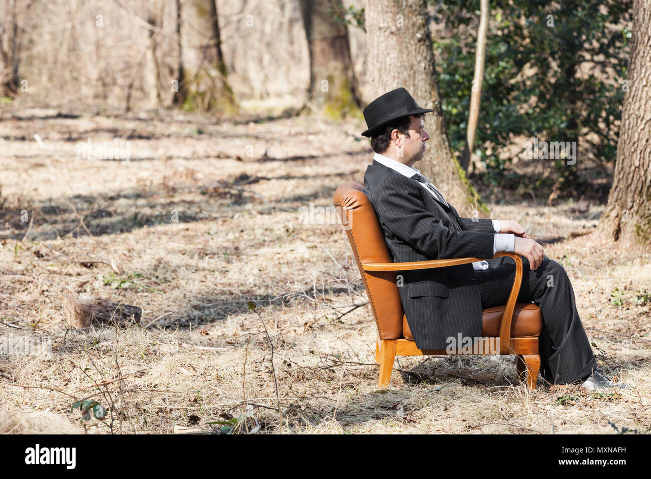 Solos en el bosque hombre sentado en un sillón, vista lateral Foto de stock