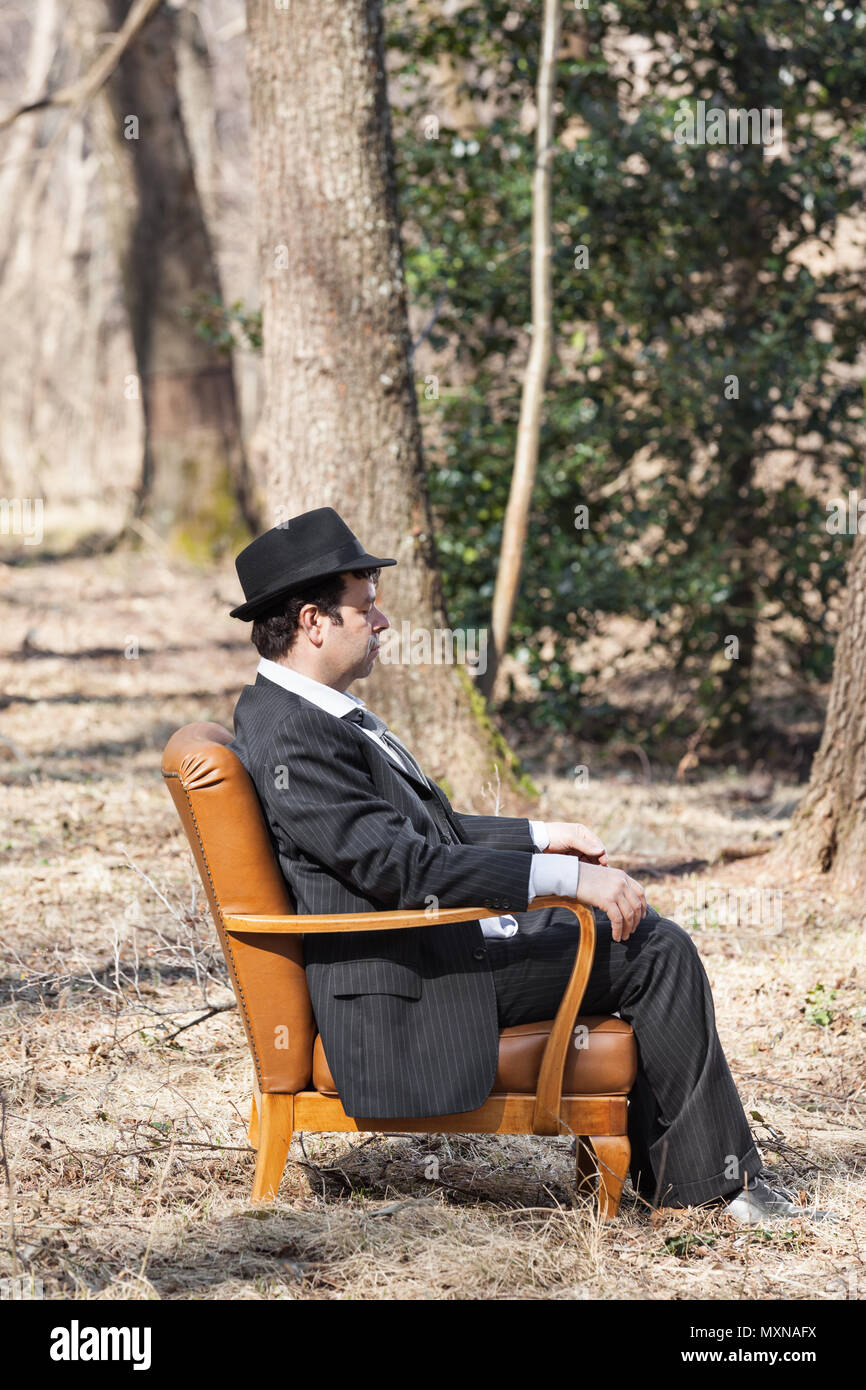 Solos en el bosque hombre sentado en un sillón Foto de stock