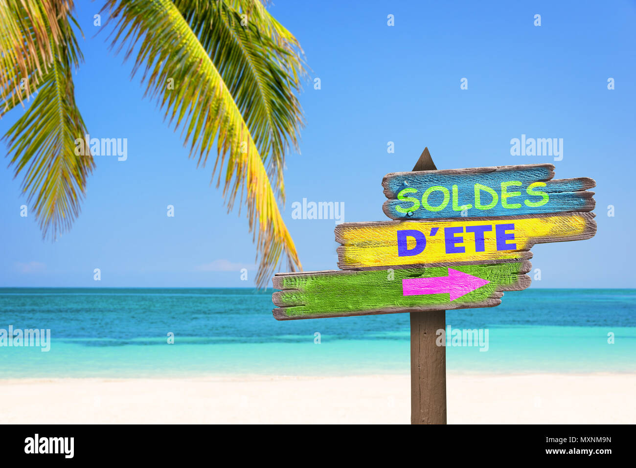 Soldes d'ete (es decir, Oferta de verano en francés) escrito en madera color pastel señales de dirección, la playa y la palmera antecedentes Foto de stock