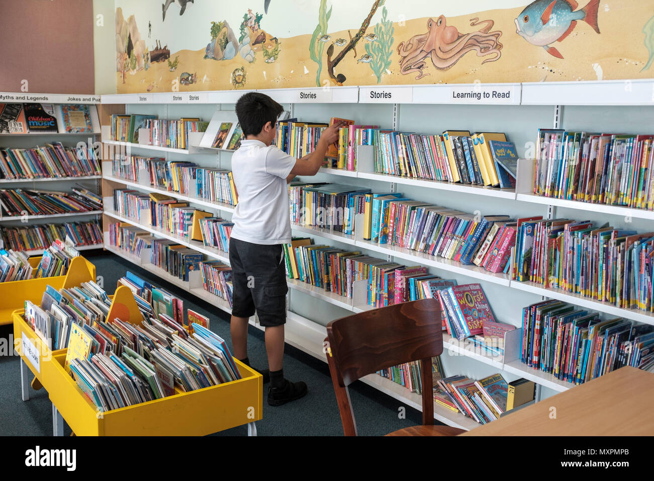 Reino Unido, Surrey, Reino Unido - 10 años colegial elegir libros en la biblioteca pública Foto de stock