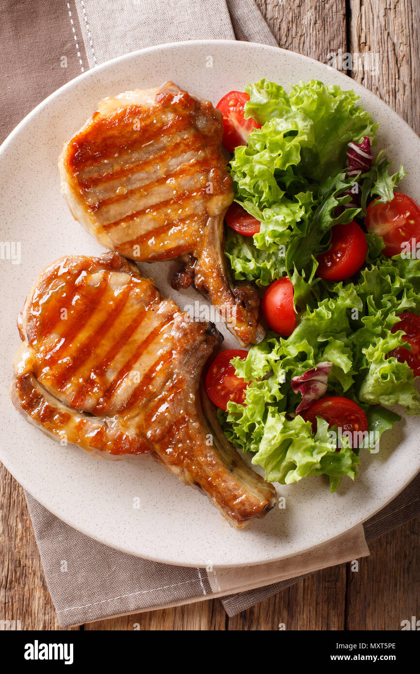 Deliciosa miel picar la carne de cerdo a la parrilla Servido con una  ensalada de verduras frescas de cerca en un plato sobre una mesa. Vista  superior de la vertical desde arriba