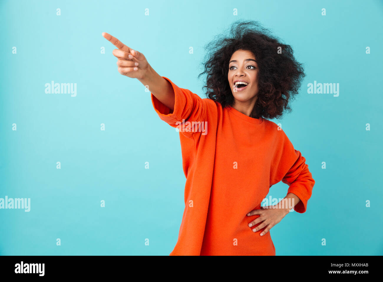 Foto de mujer americana en camiseta roja mirando a un lado y señalando con  el dedo índice sobre copyspace aislado sobre fondo azul Fotografía de stock  - Alamy