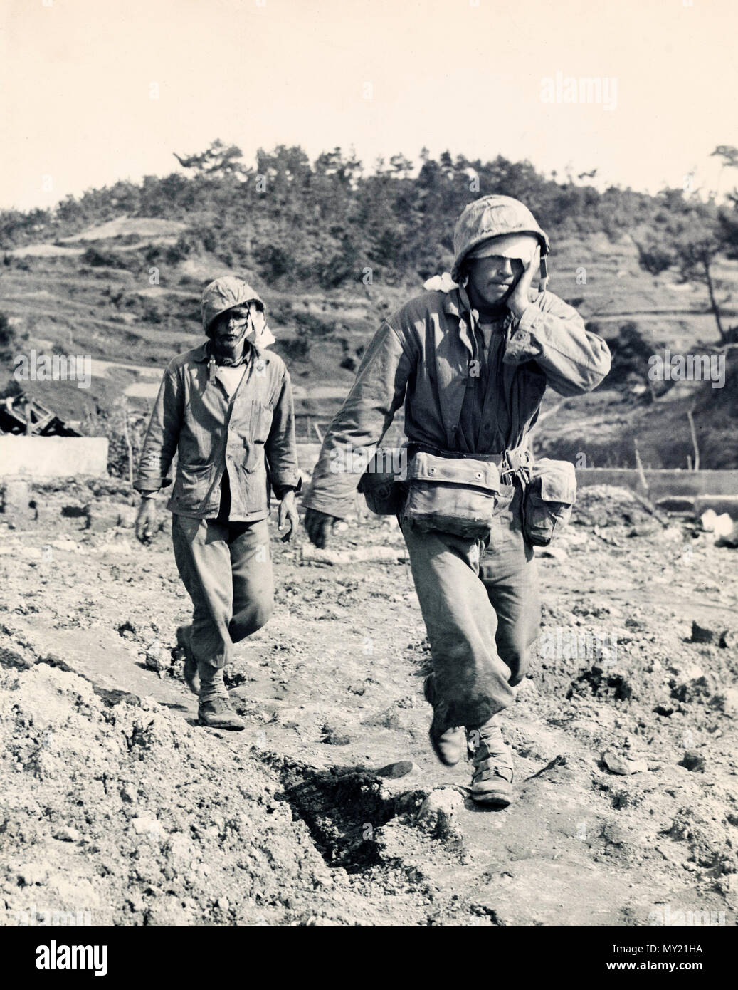 Un infante de marina y un oficial de la Naval con heridas en la cabeza caminando hacia la retaguardia en Okinawa Foto de stock