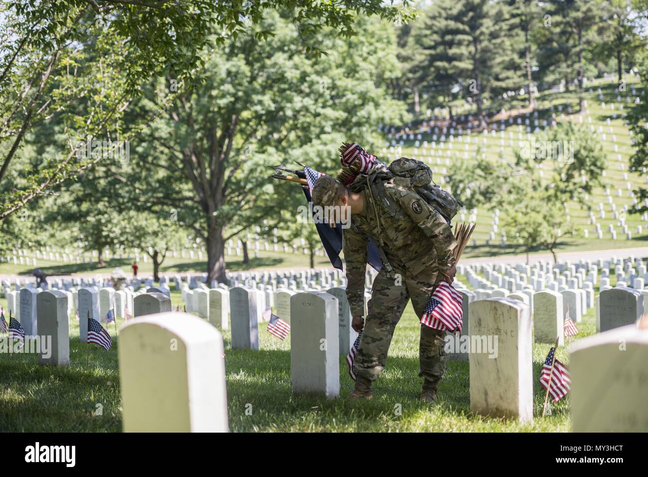 Un soldado del Regimiento de la infantería de 3d los E.E.U.U. (la vieja guardia) coloca banderas estadounidenses en lápidas en la Sección 43 durante las banderas en el Cementerio Nacional de Arlington, Arlington, Virginia, 24 de mayo de 2018, 24 de mayo de 2018. Por más de 60 años, los soldados de la vieja guardia han honrado a nuestra nación los héroes caídos colocando banderas estadounidenses en fosas comunes para los miembros del servicio ambos sepultados en el Cementerio Nacional de Arlington y los soldados estadounidenses" y aviadores's Home National Cemetery justo antes del fin de semana de Memorial Day. Dentro de las cuatro horas, más de 1, 000 soldados colocados 234, 537 banderas en frente de cada lápida y Columba Foto de stock