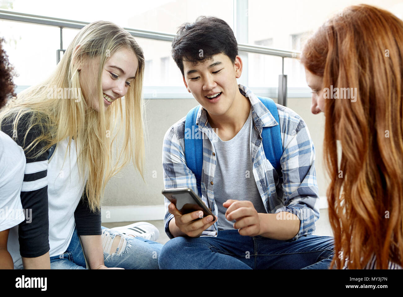 Estudiante mostrando teléfono inteligente a sus compañeros de clase Foto de stock