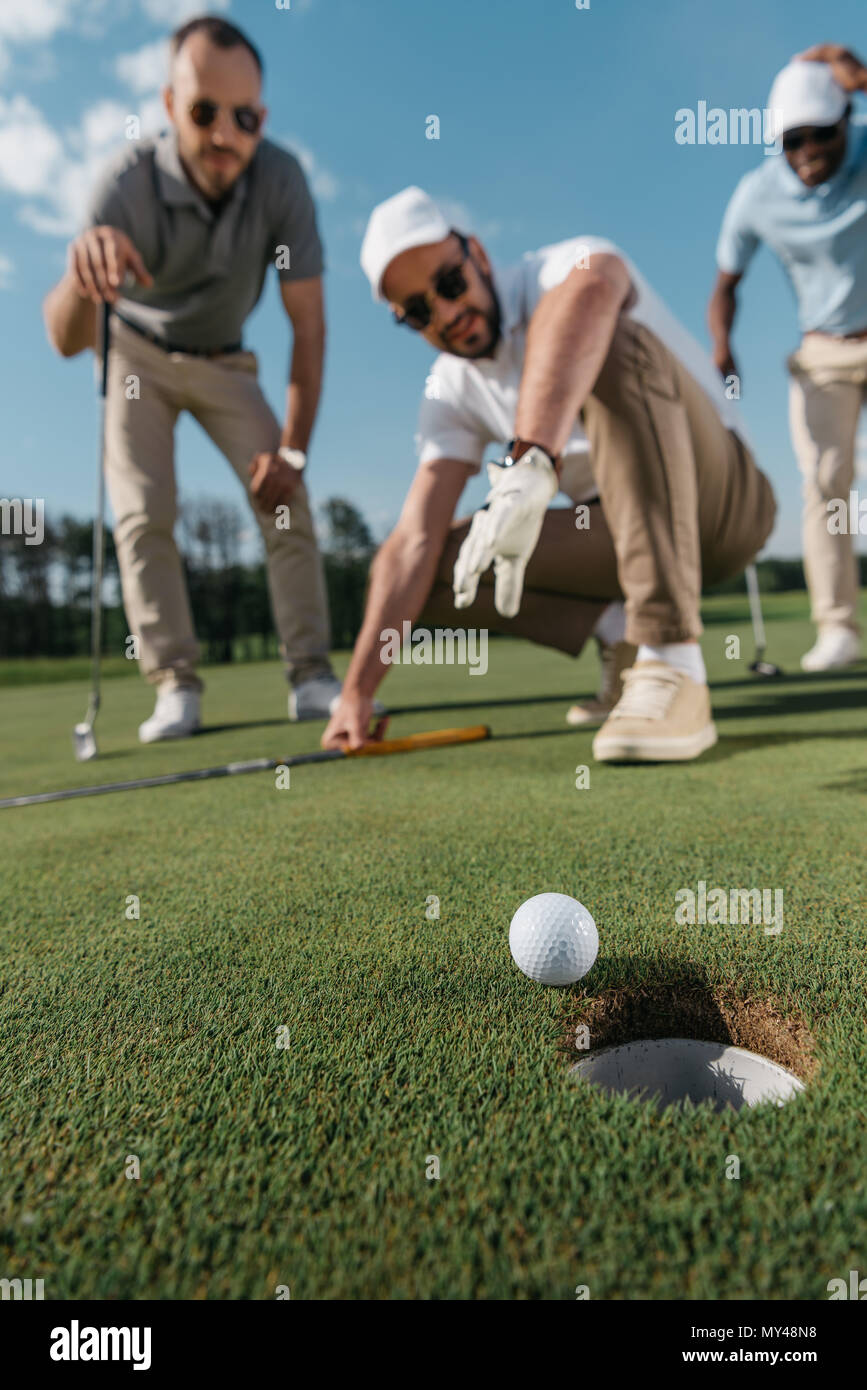 Los jugadores de golf profesionales jóvenes mirando la bola cerca del agujero Foto de stock