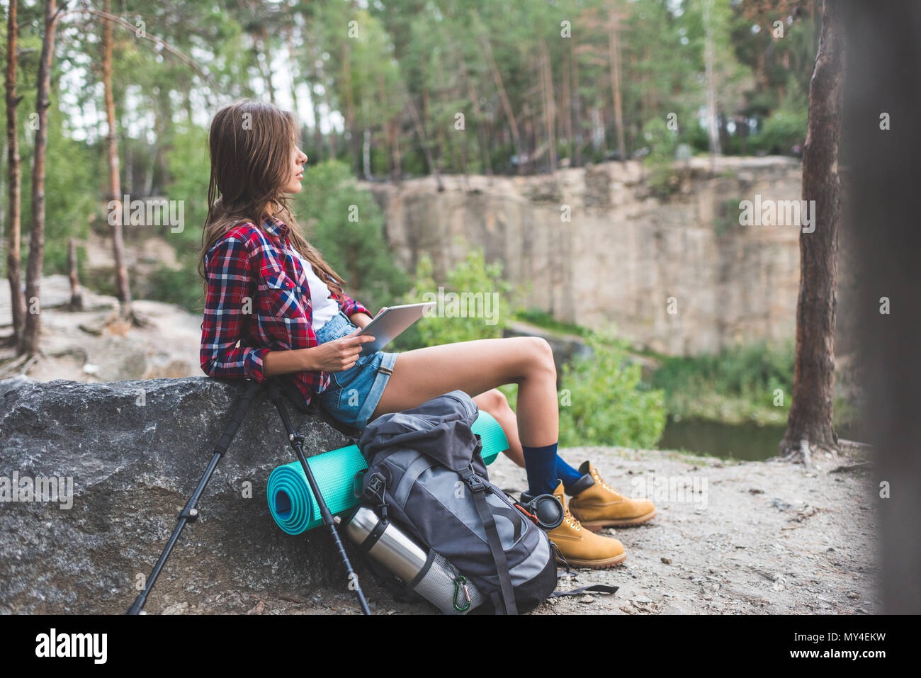 Excursionista joven mujer con mochila y trekking polos utilizando tablet en  la naturaleza Fotografía de stock - Alamy