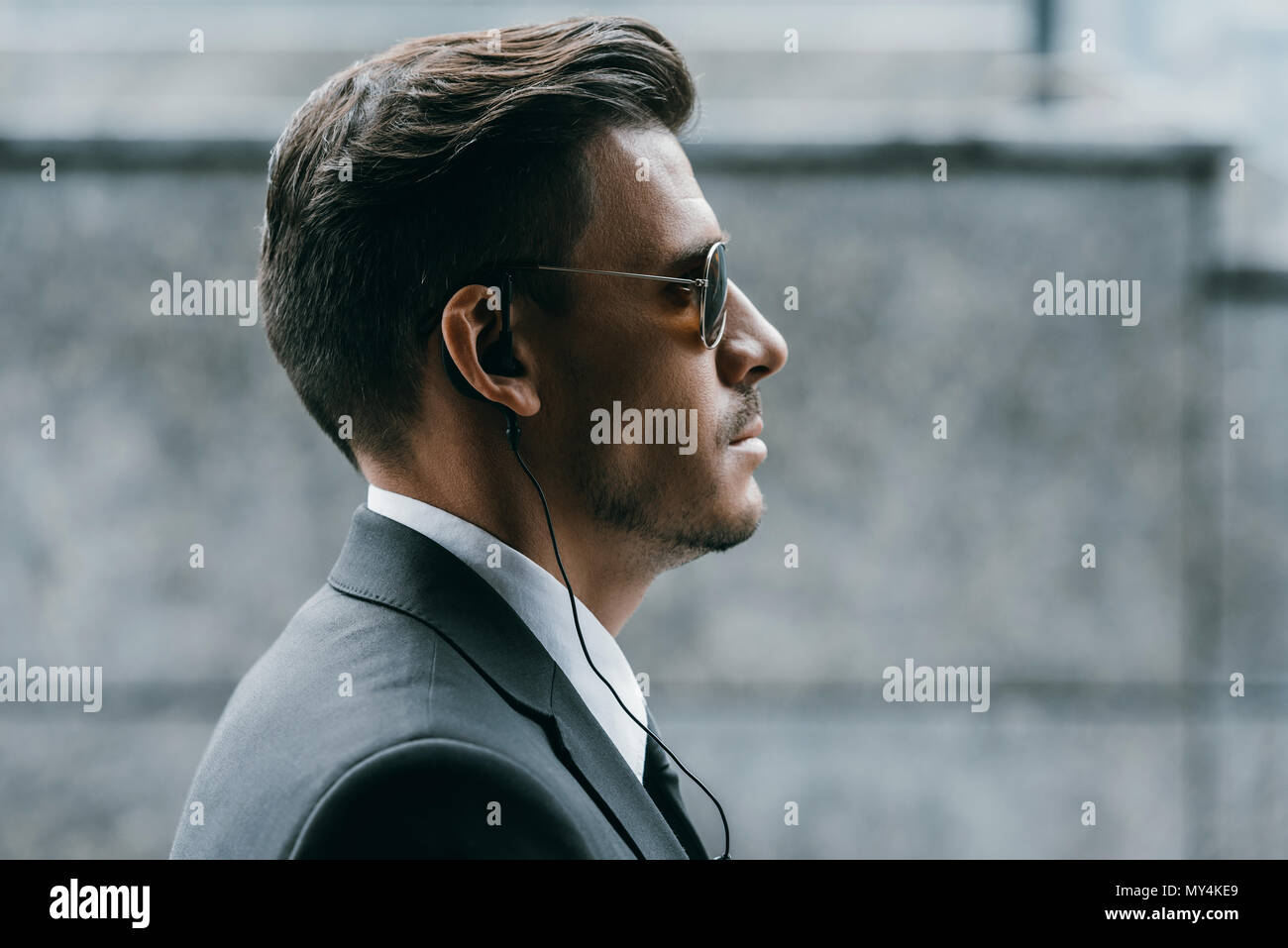 Perfil de guardaespaldas guapo con gafas de sol y seguridad auricular Foto de stock
