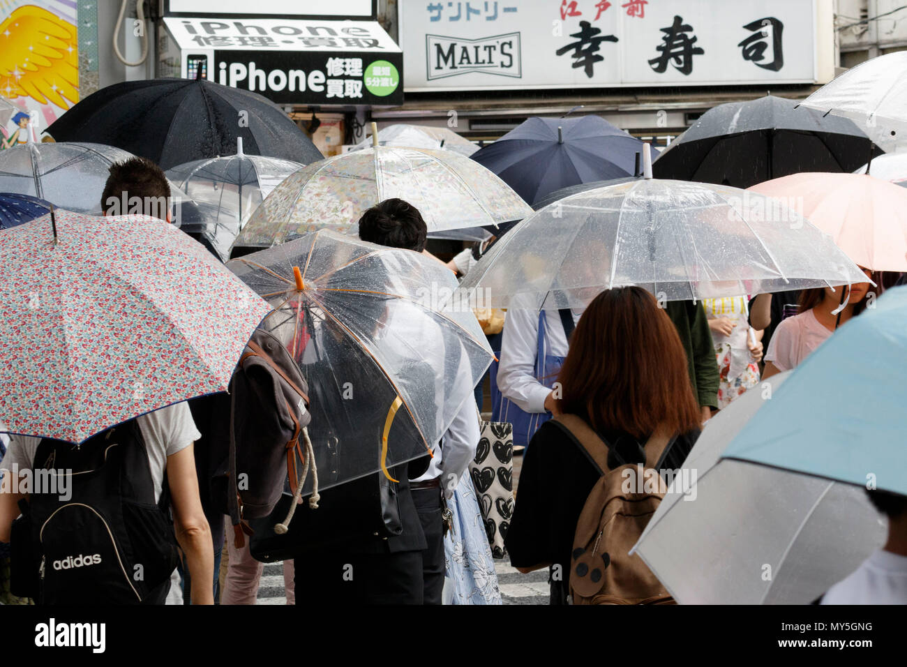 Los peatones mantenga un paraguas bajo la lluvia en Tokio, de junio de 2018, Japón. La Agencia Meteorológica de Japón anunció el pronto inicio de la de lluvias en