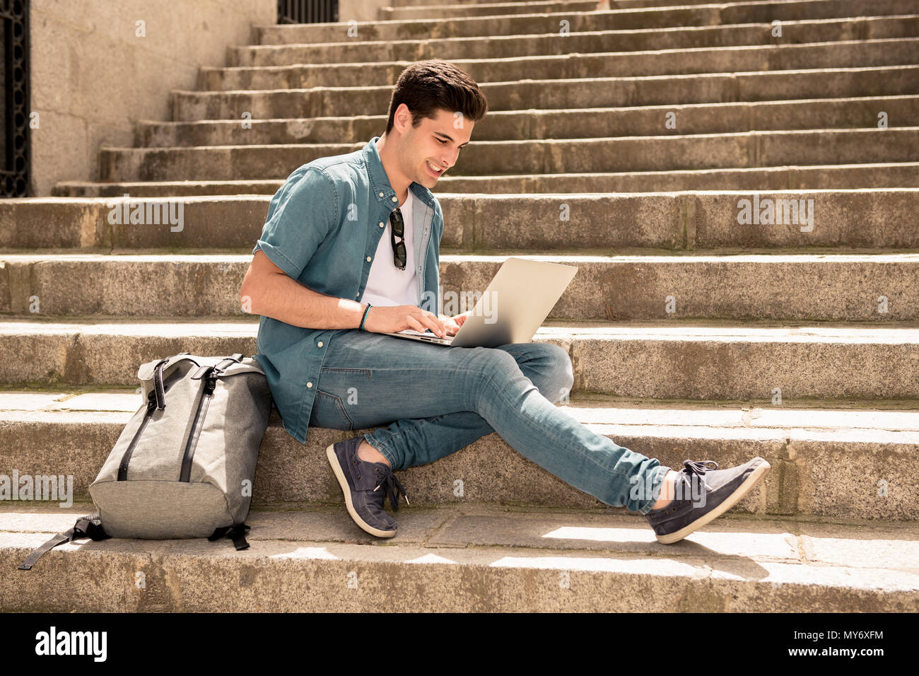 Joven apuesto hombre moderno en smart ropa casual con ordenador portátil en  la ciudad sentada en las escaleras exteriores. En los estudiantes, autónomo  y navegación Fotografía de stock - Alamy