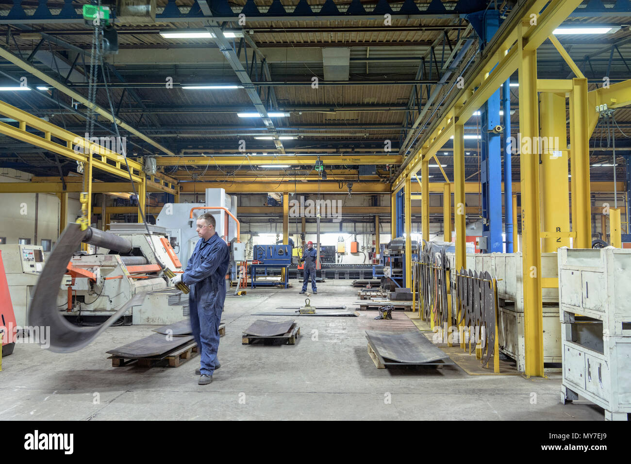 Los trabajadores con las máquinas de curvado de acero en la fábrica de ingeniería Foto de stock
