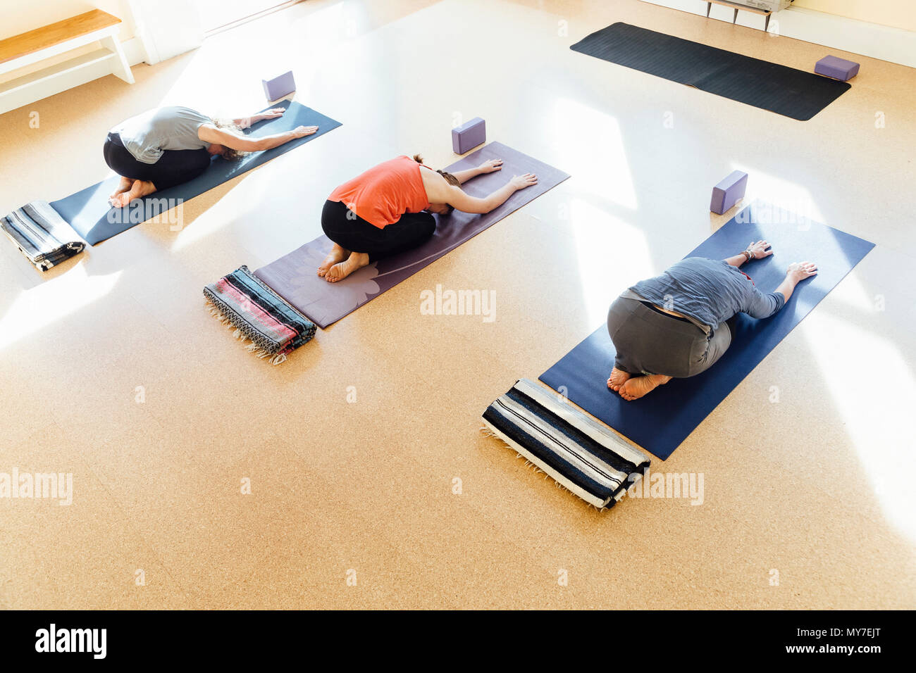 Tres mujeres practicando la postura del niño (balasana) en yoga studio Foto de stock