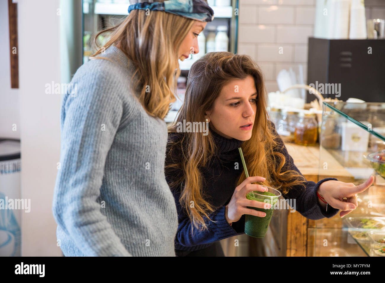 Joven y amigo buscando alimentos frescos vitrina en cafe Foto de stock