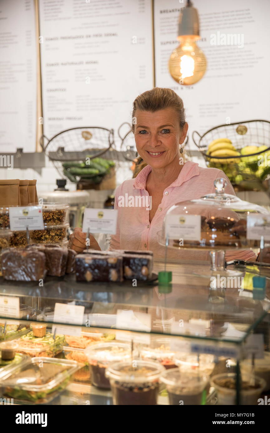 Retrato de ayudante de ventas de café, de pie detrás del mostrador, sonriendo Foto de stock