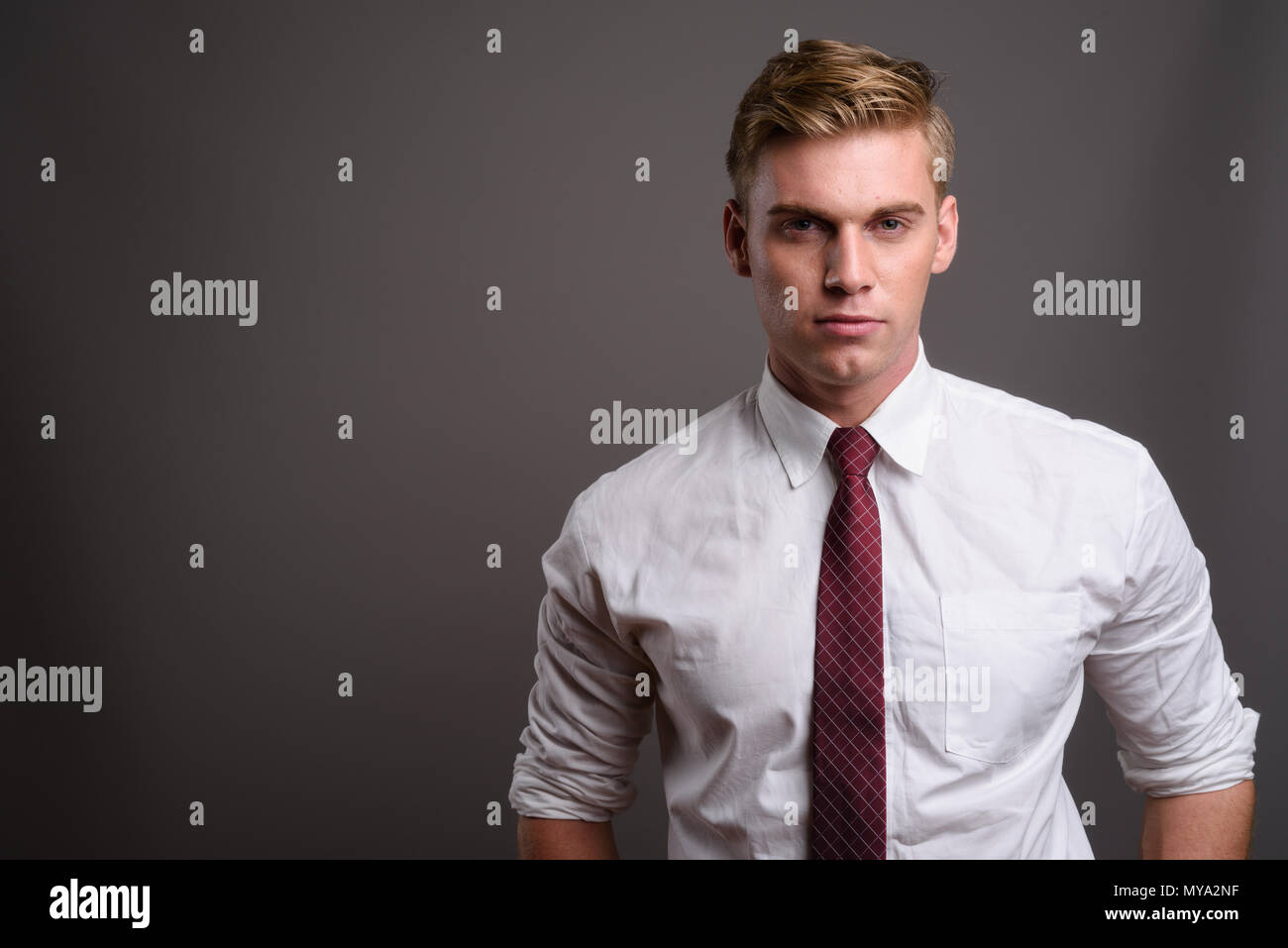 Empresario joven apuesto con el pelo rubio contra backgrou gris Foto de stock