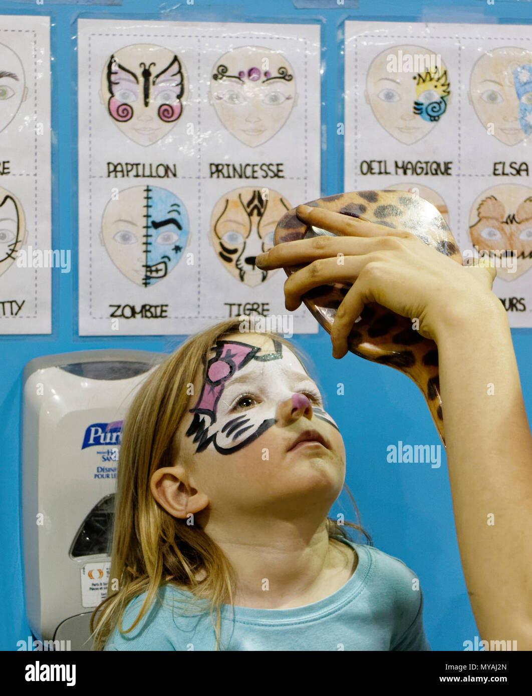 Una chica joven (3 años) admirando su nueva Hello Kitty pintura facial en un espejo Foto de stock