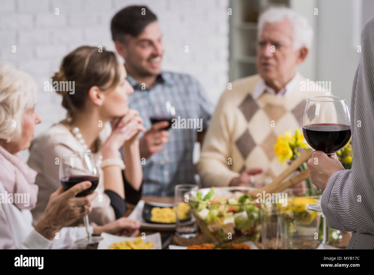 Familia Feliz sentado al lado de la tabla durante la comida, beber el vino. Foto de stock