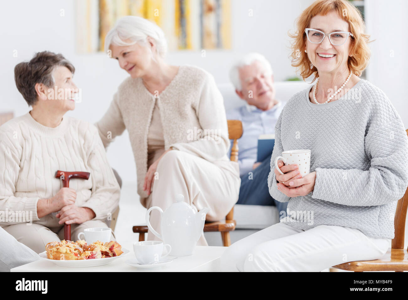 Elegante feliz anciana beber té en club senior Foto de stock