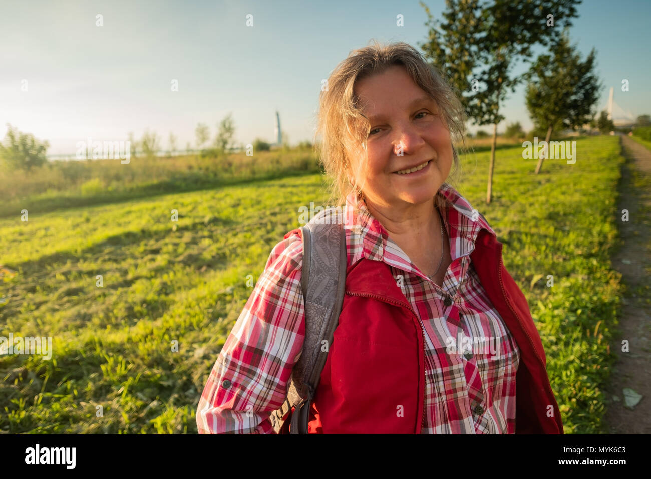 Close Up retrato de mujer de edad feliz de pie fuera en verano sobre fondo de campo. Foto de stock