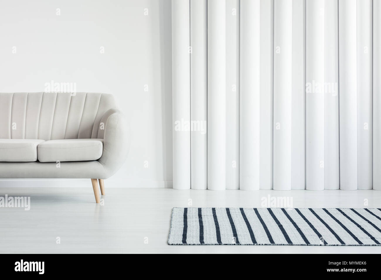 Beige blanco sofá en el salón interior con manta rayas y los tubos de pared con espacio de copia Foto de stock