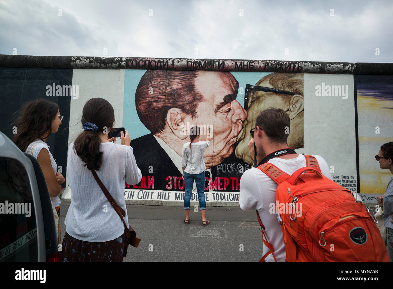 Berlín. Alemania. Los turistas posar para fotos enfrente de uno de los remanentes del muro de Berlín en el East Side Gallery. Los turistas posan para ph Foto de stock