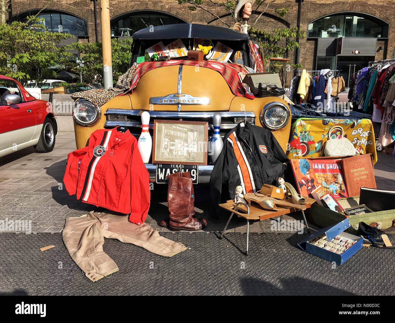 St estable, Londres, Reino Unido. 23 abr, 2017. Ropa de moda retro se  alinearon junto a un automóvil Chevrolet amarillo vintage en el Classic car  boot sale en granero Square, Kings Cross,