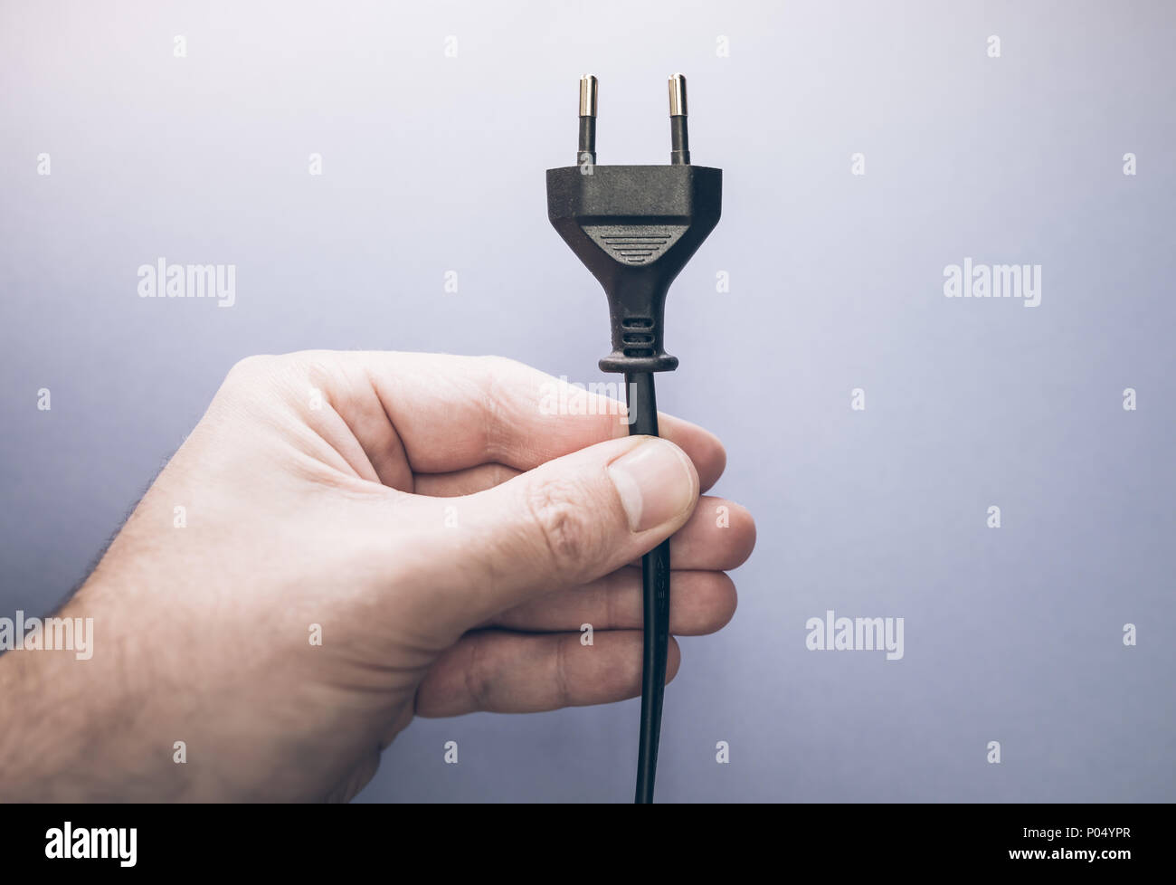 Hombre mano sujetando el enchufe eléctrico Foto de stock