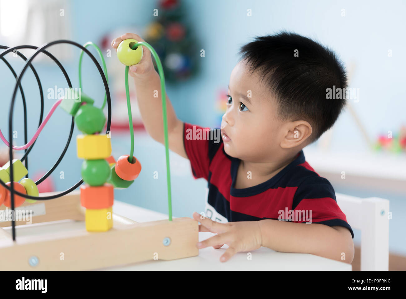 Adorable Niño Asiático Baby Boy sentado en una silla y jugar con los juguetes en el desarrollo de color en el hogar. Foto de stock