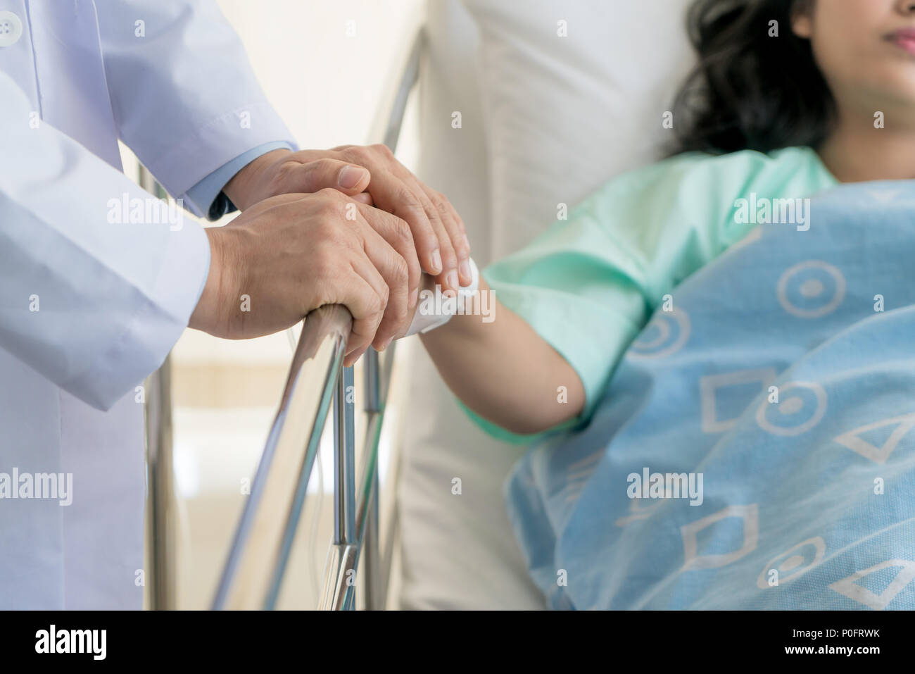 Hombre simpático médico manos sosteniendo la mano del paciente sentado al escritorio de aliento, de empatía, vítores y apoyo al examen médico. Malo nuevo Foto de stock