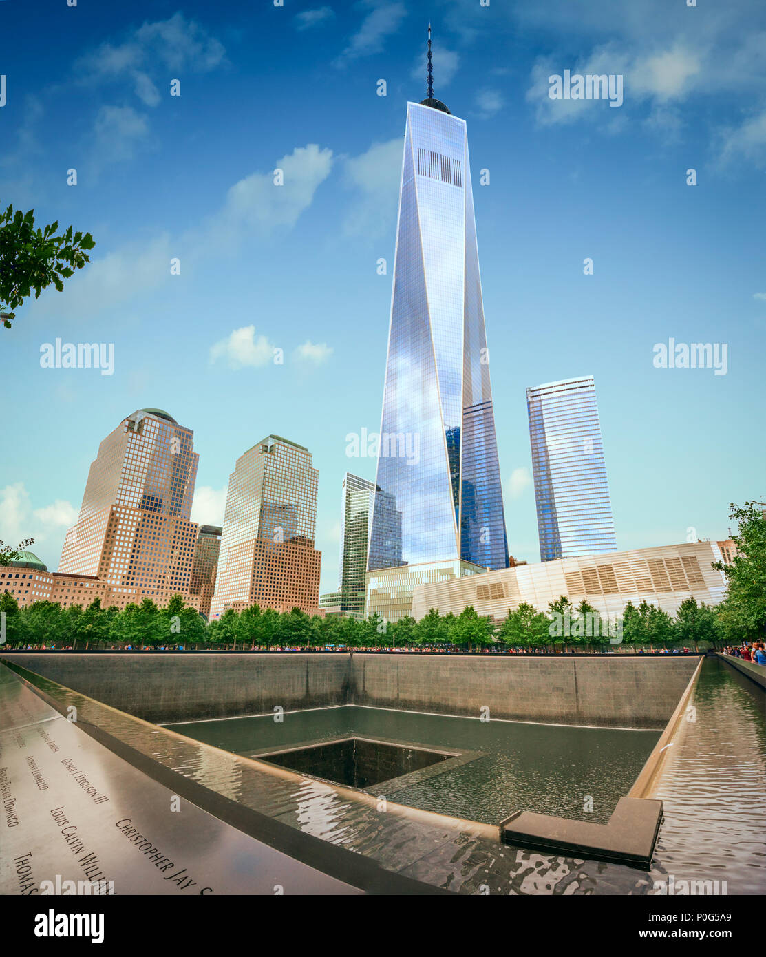 En el primer plano el monumento a las víctimas de la tragedia de 9/11 y en el fondo el nuevo World Trade Center se eleva de manera desafiante Foto de stock