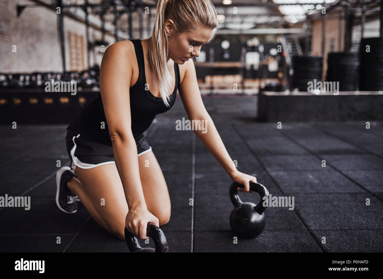 Mujer joven rubia centrada en ropa para hacer El ejercicio solo con pesas en el gimnasio Fotografía de stock - Alamy