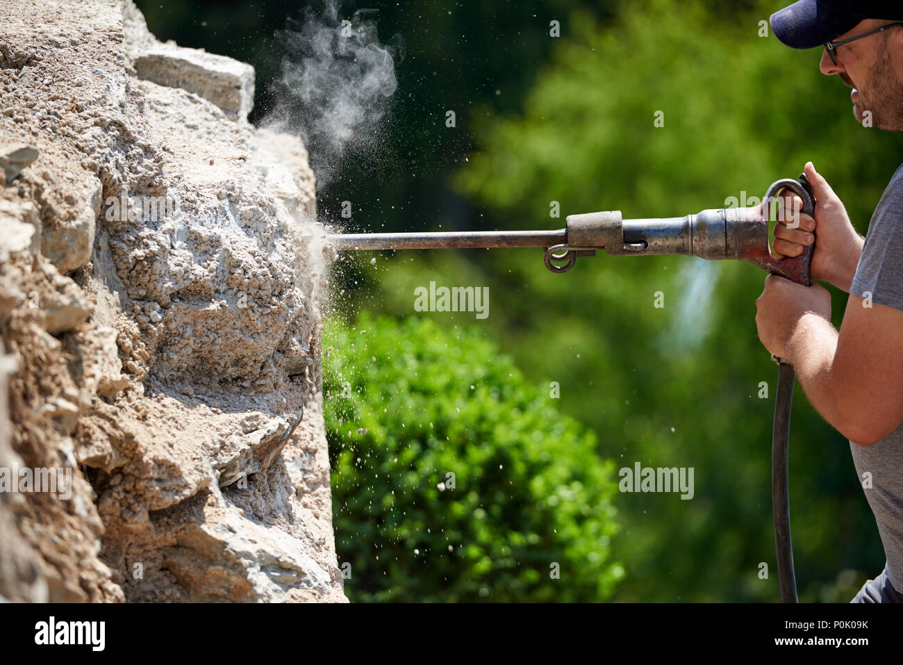 Trabajador de la construcción con jackhammer demoler una pared, detalle industrial Foto de stock