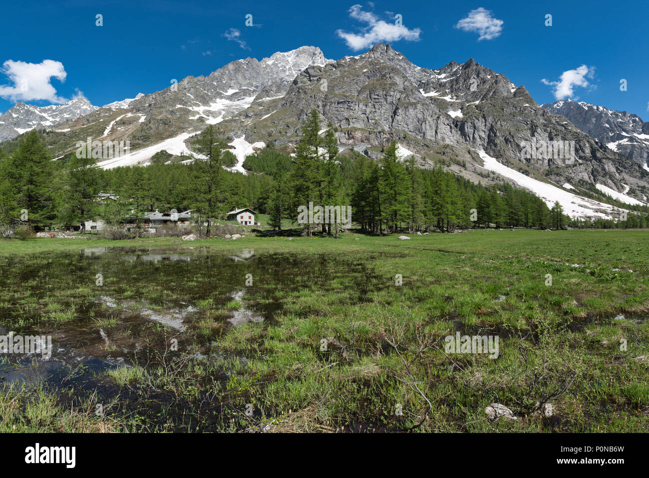 Hermoso paisaje de Val Ferret en la temporada de primavera con lago, Little Village, alerces y montañas Grandes Jorasses en el fondo, Italia Foto de stock