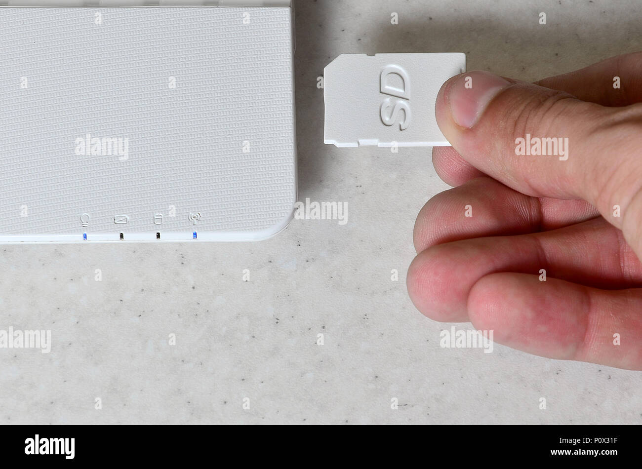 Un hombre mano inserta una tarjeta SD compacto blanco en la entrada  correspondiente en el lado blanco de la netbook. El hombre utiliza las  tecnologías modernas para almacenar memor Fotografía de stock -