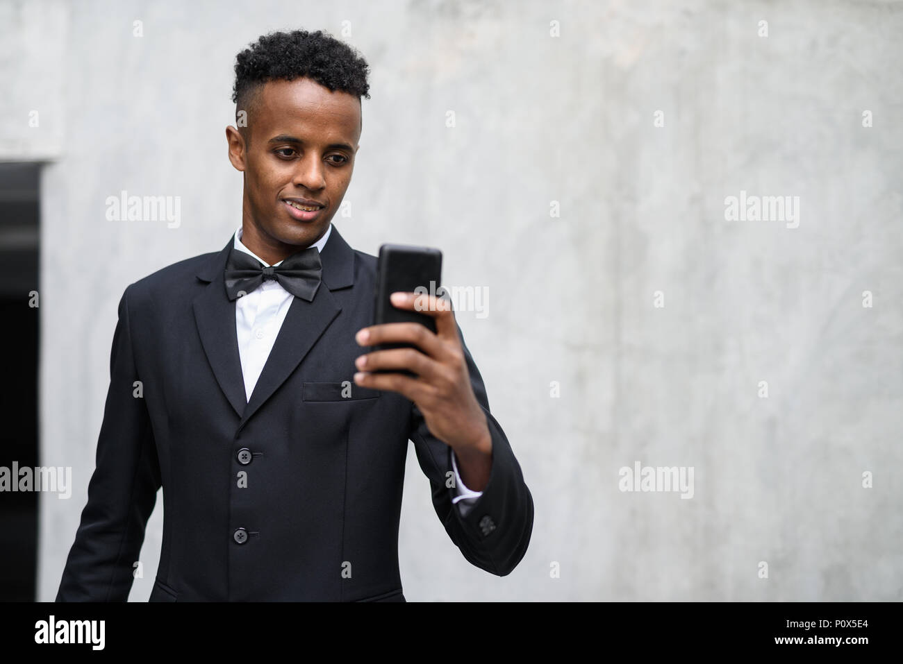 Apuesto joven empresario africano vistiendo traje contra el hormigón Foto de stock