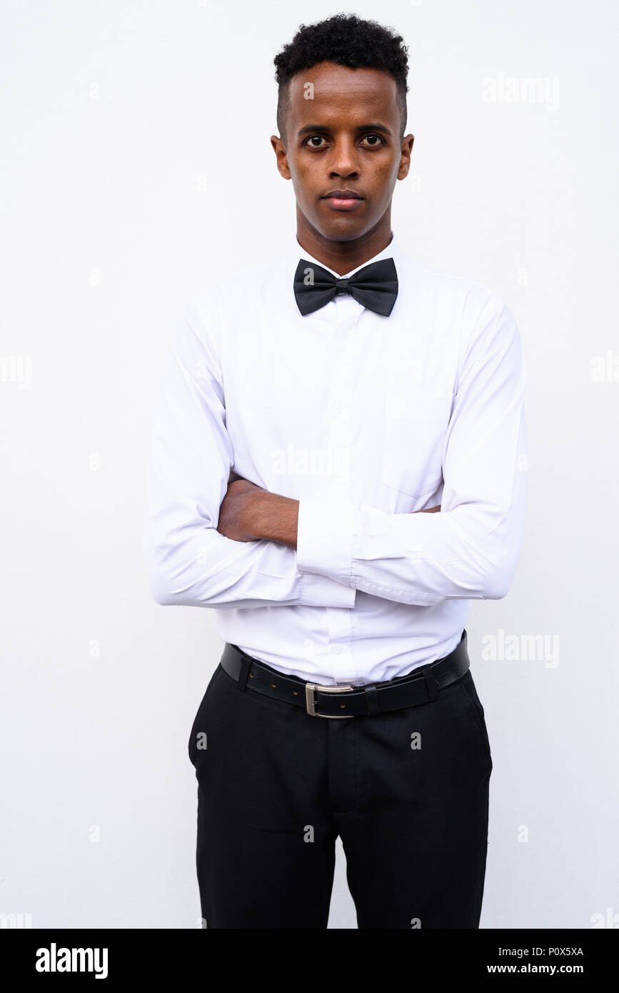 Apuesto joven empresario africano luciendo pajarita contra un blanco Foto de stock