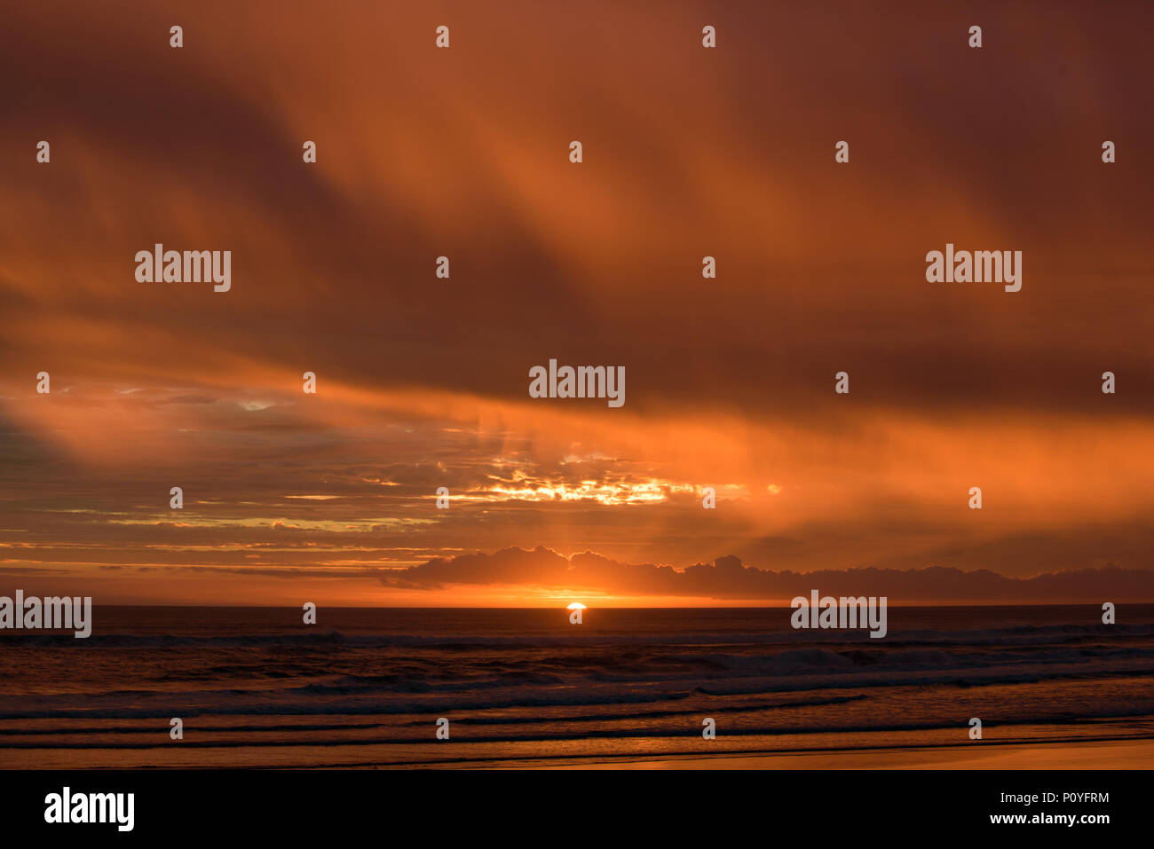 Muriwai Beach al atardecer con las nubes de colores, Nueva Zelanda Foto de stock