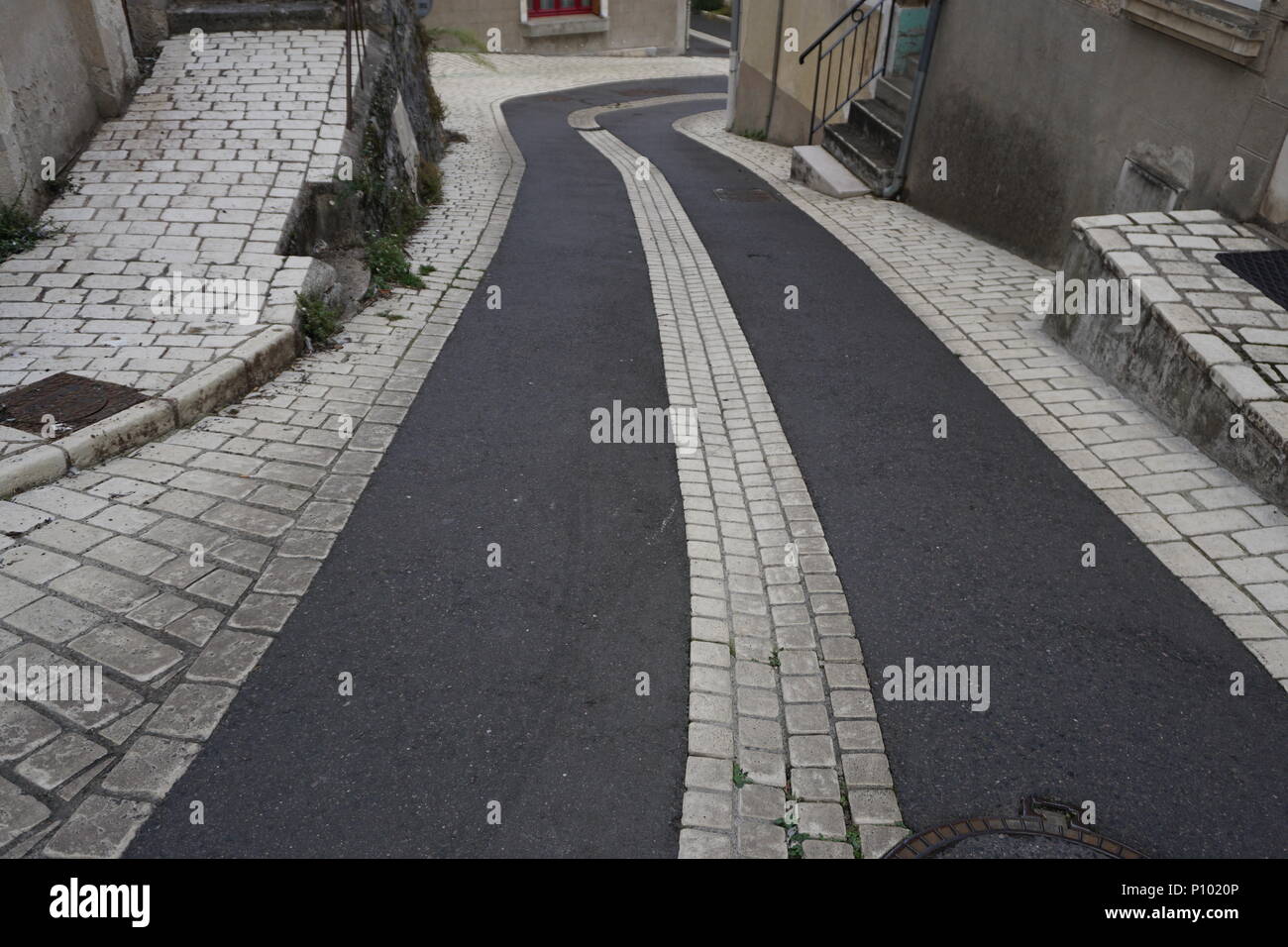 Antigua calle de guijarros y acera en un pequeño pueblo francés Foto de stock