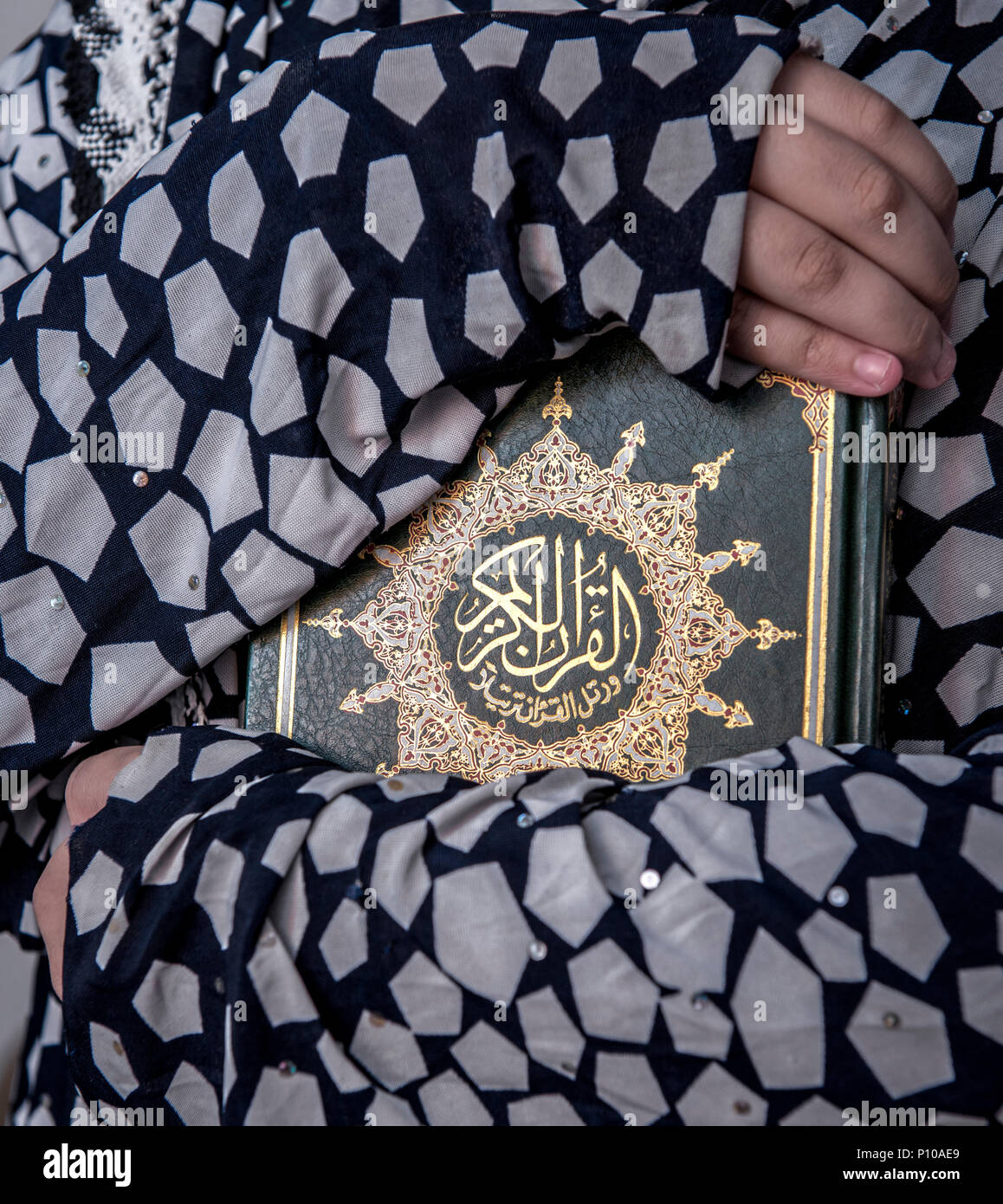 Dos brazos de niña musulmana abrazando Libro Sagrado del Corán Foto de stock