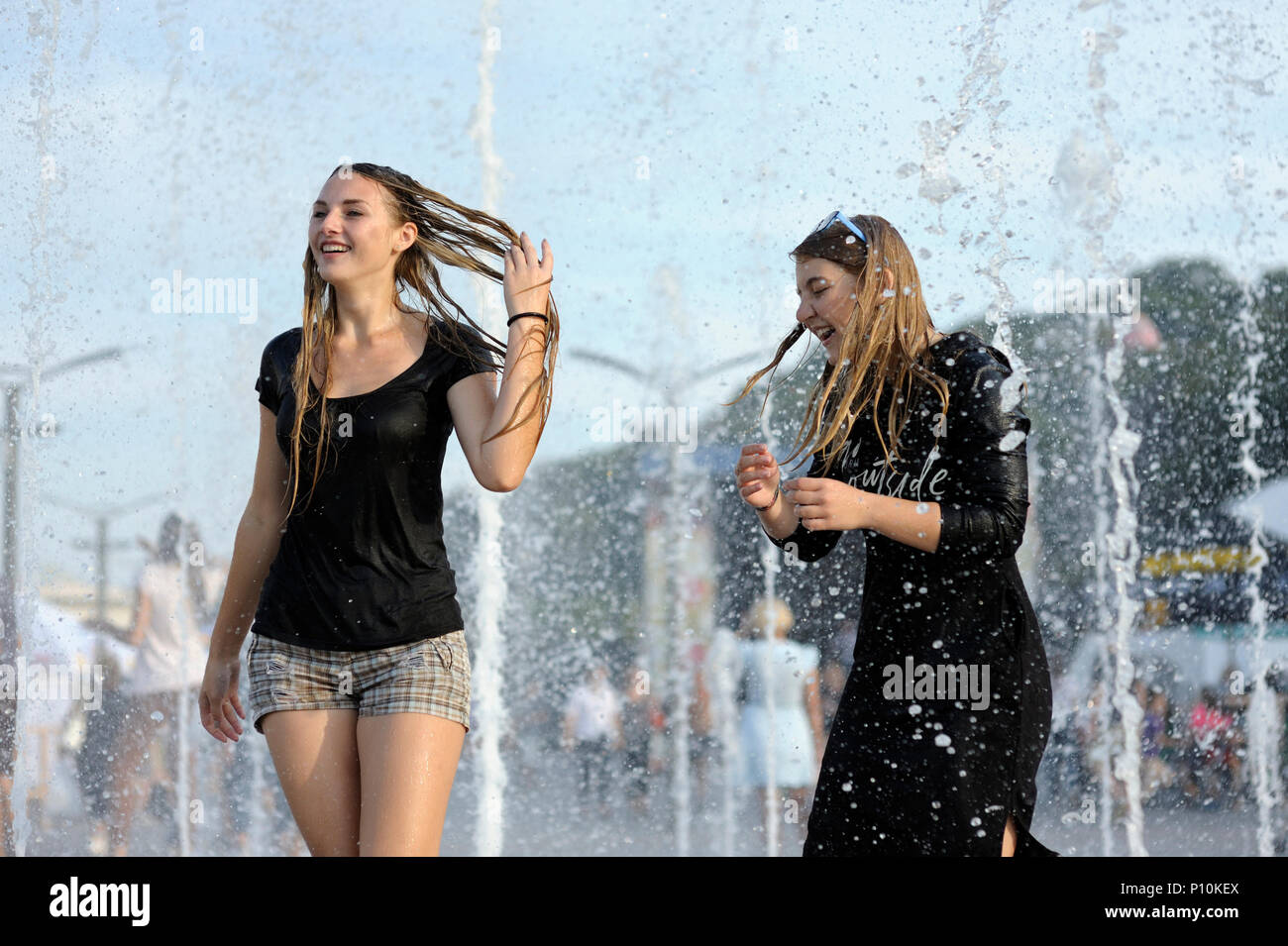 Calor Fuerte en la ciudad: niños jugando con chorros de agua de una fuente en la plaza. Junio 5, 2018. Kiev, Ucrania Foto de stock