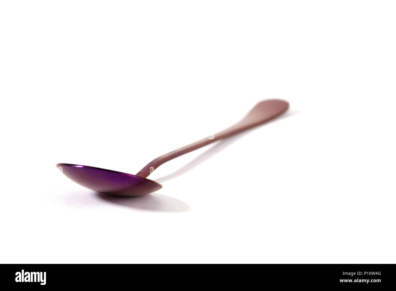 Cuchara de acero inoxidable coloridos púrpura aislado sobre fondo blanco - Enfoque en primer plano con poca profundidad de campo Foto de stock