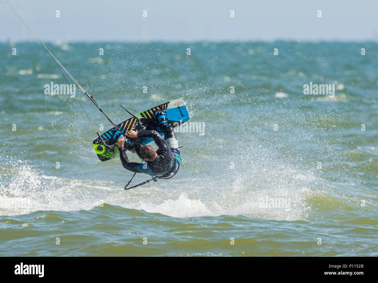 Deportes extremos como un hombre kitesurf vuela al revés en el aire como parte de un truco en el mar, en el Reino Unido. Foto de stock