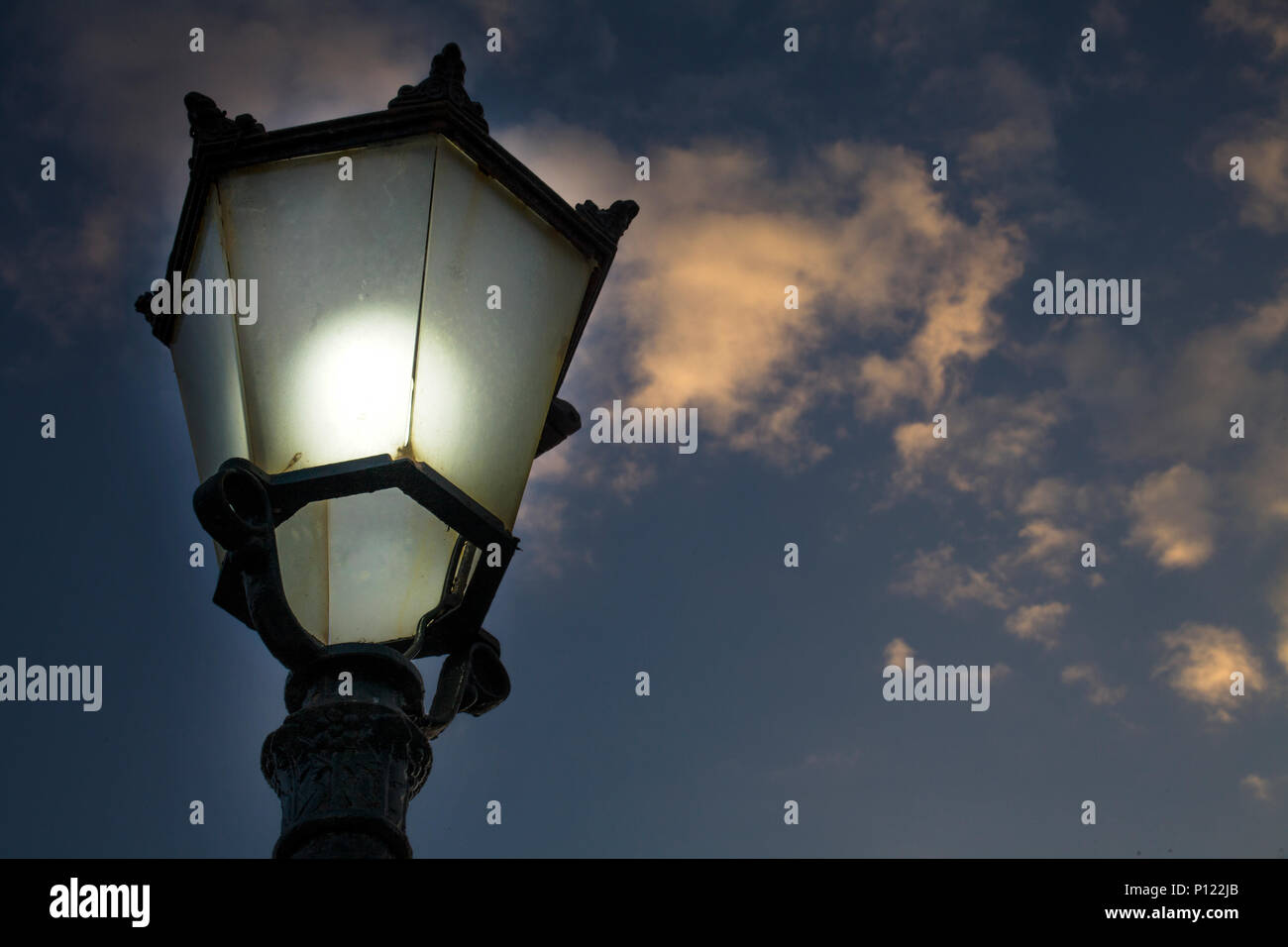 Una bombilla incandescente adecuadamente cubiertas con vidrio brillando en  el poste de la luz de la calle de antigüedades medievales europeos.El poste  de la luz está hecha de acero fundido es hecho