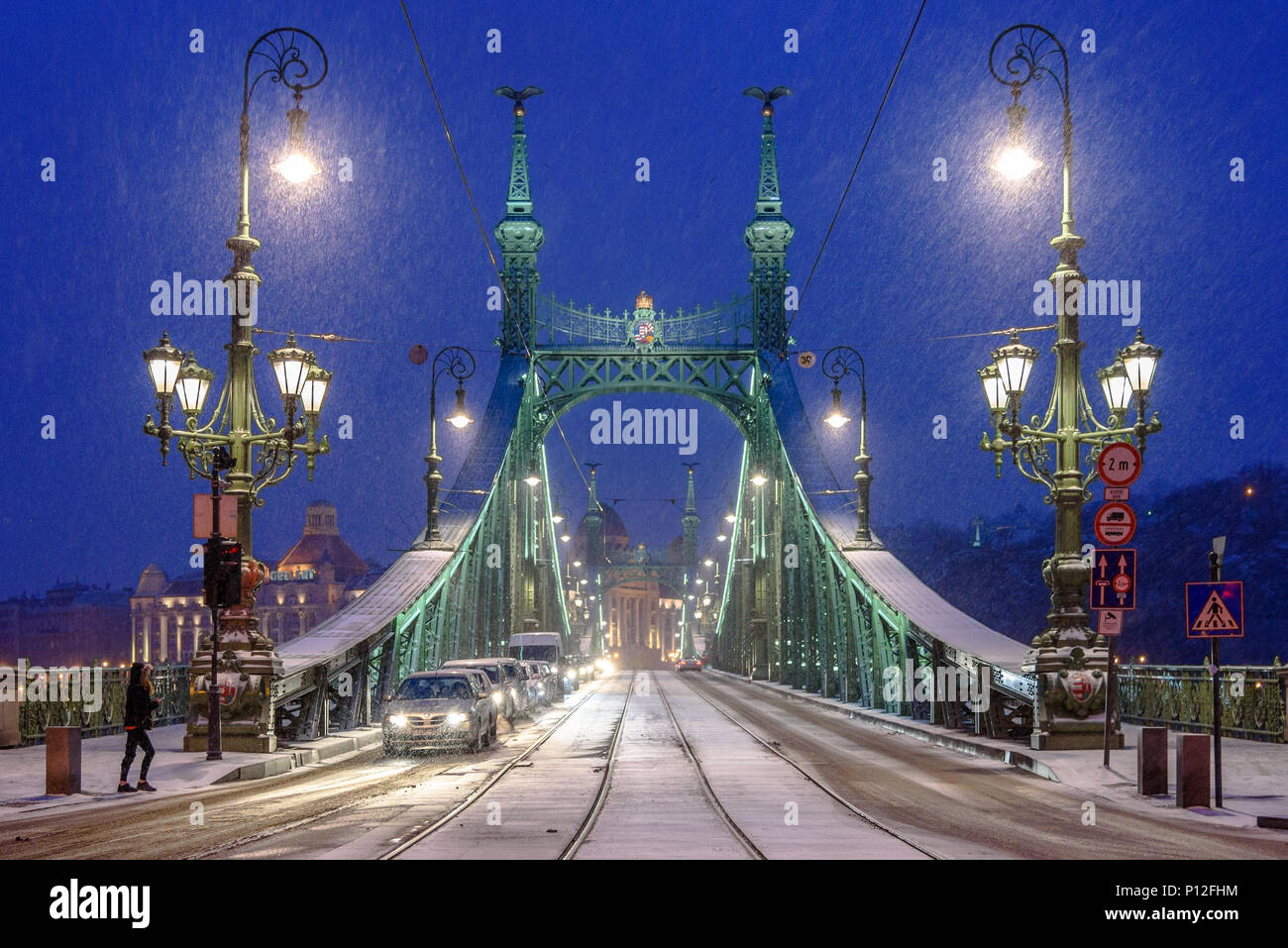 Los coches se alinearon en una luz sobre la nieve cubrió Puente Liberty en Budapest Foto de stock