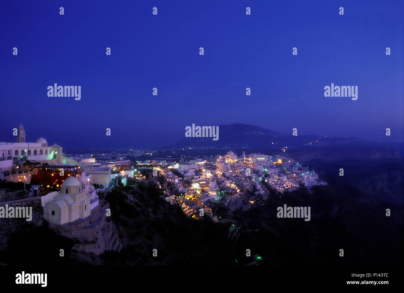 Isla griega de Thira (Santorini), vistas de los acantilados, mirando al sur, mostrando la ciudad de Thira a lo largo del borde del precipicio al anochecer, Grecia Foto de stock